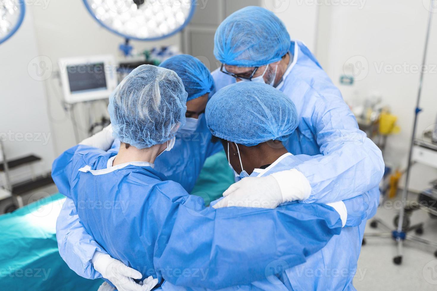 Medical professionals embracing each other in ICU. Doctors and nurses are in protective coveralls after successful treatment. They are at hospital during COVID-19. photo