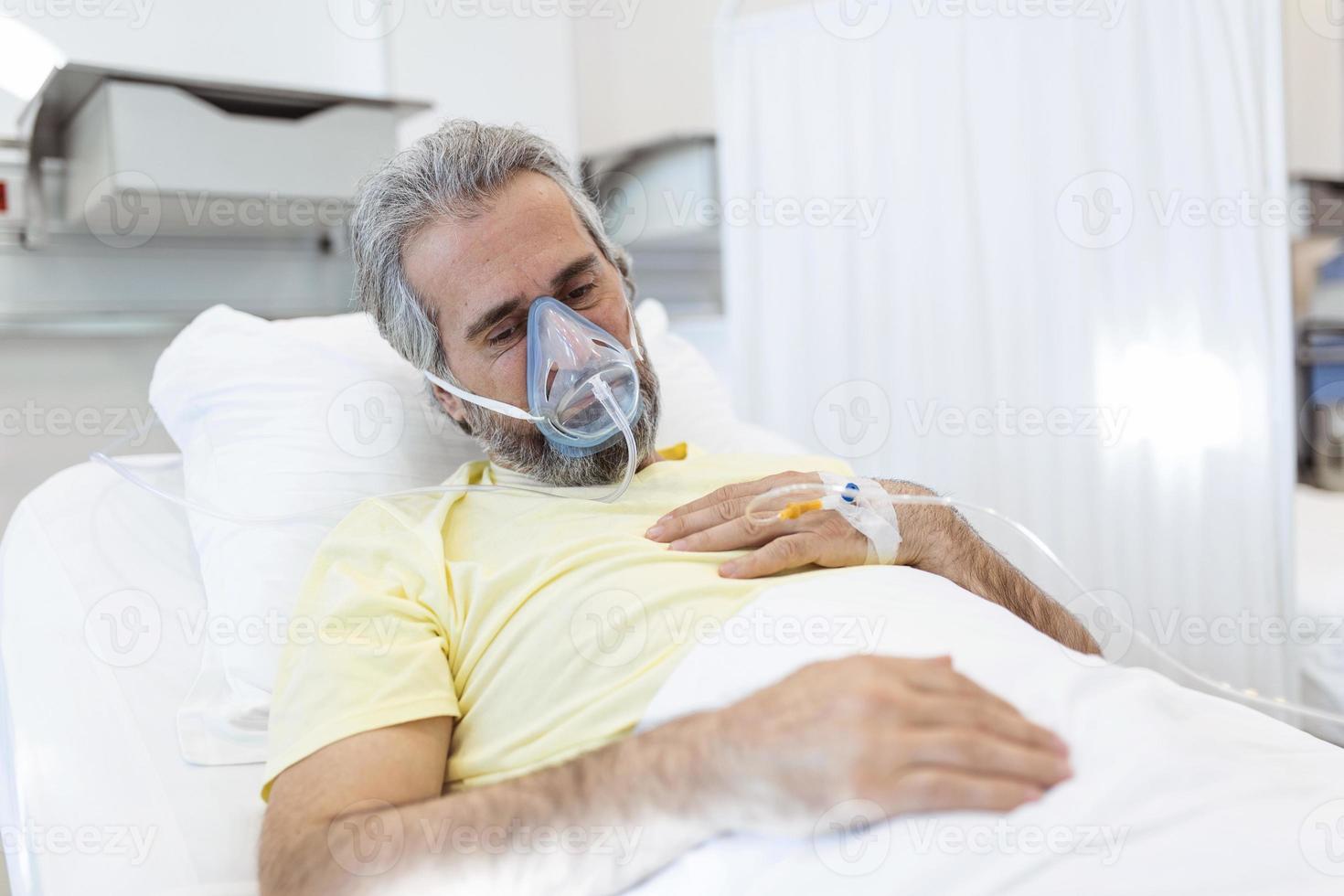 Portrait of retired senior man breathing slowly with oxygen mask during coronavirus covid-19 outbreak. Old sick man lying in hospital bed, getting treatment for deadly infection photo