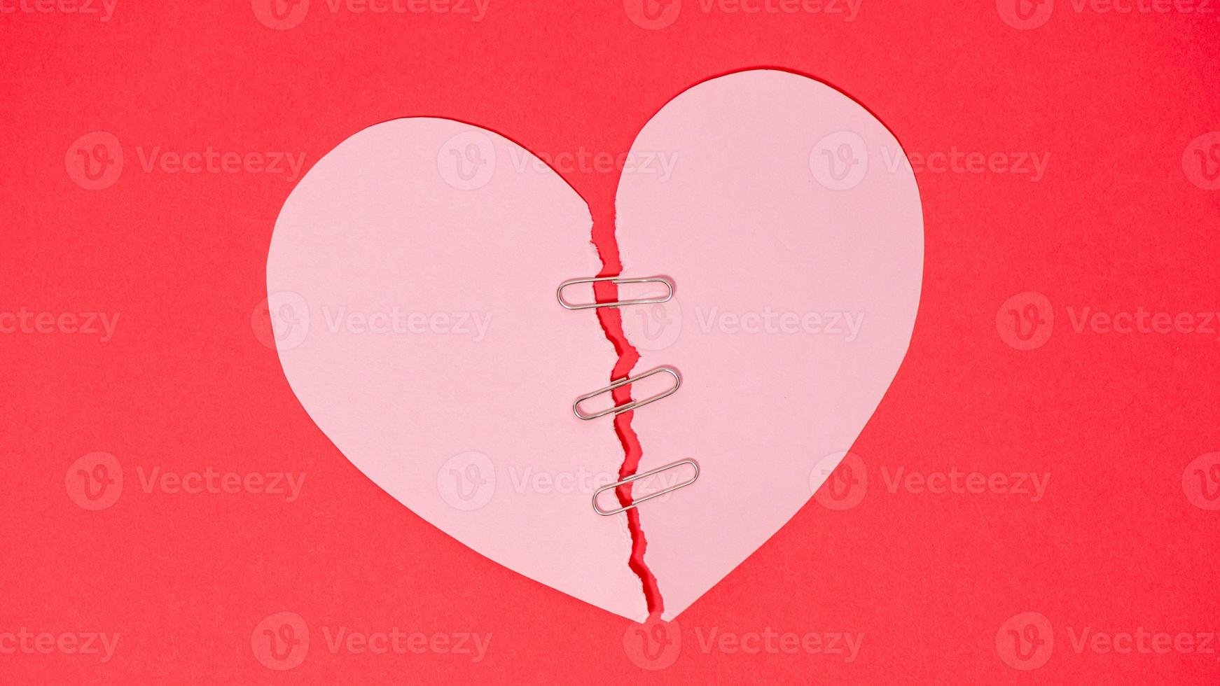 Shape of broken heart on red paper background. photo