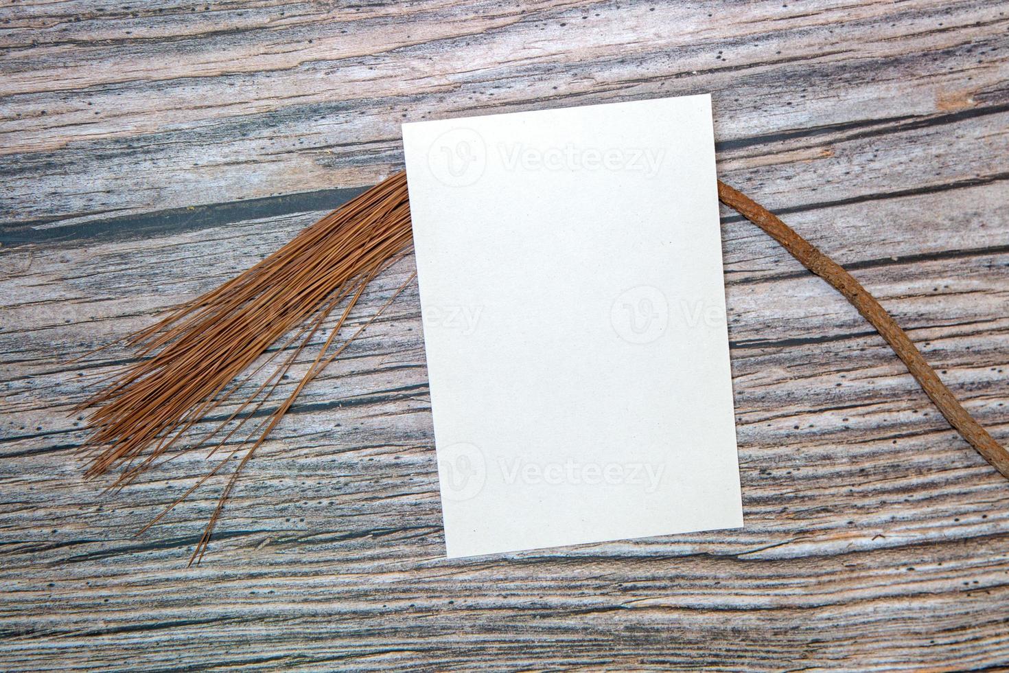 A5 paper greeting card mockup with dry leaves on wooden background photo