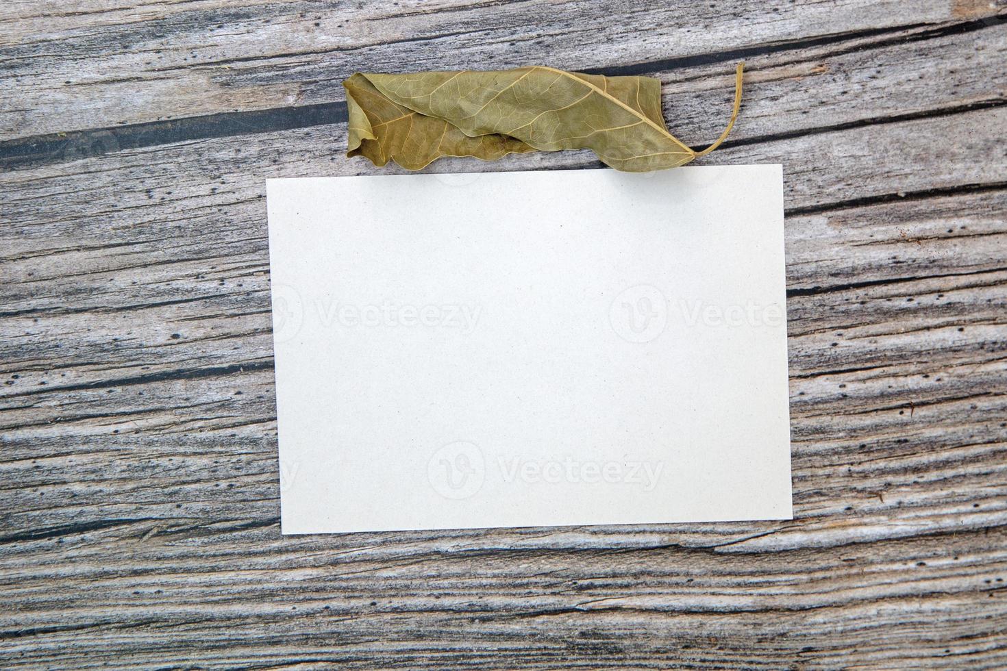 A5 paper greeting card mockup with dry leaves on wooden background photo