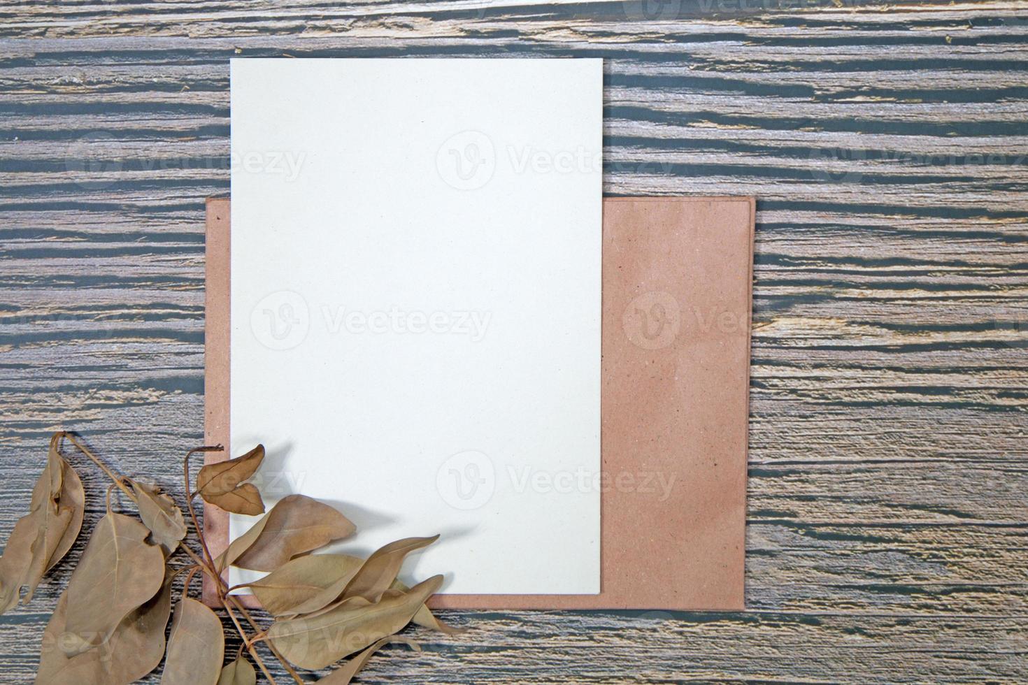 A5 paper greeting card mockup with dry leaves on wooden background photo
