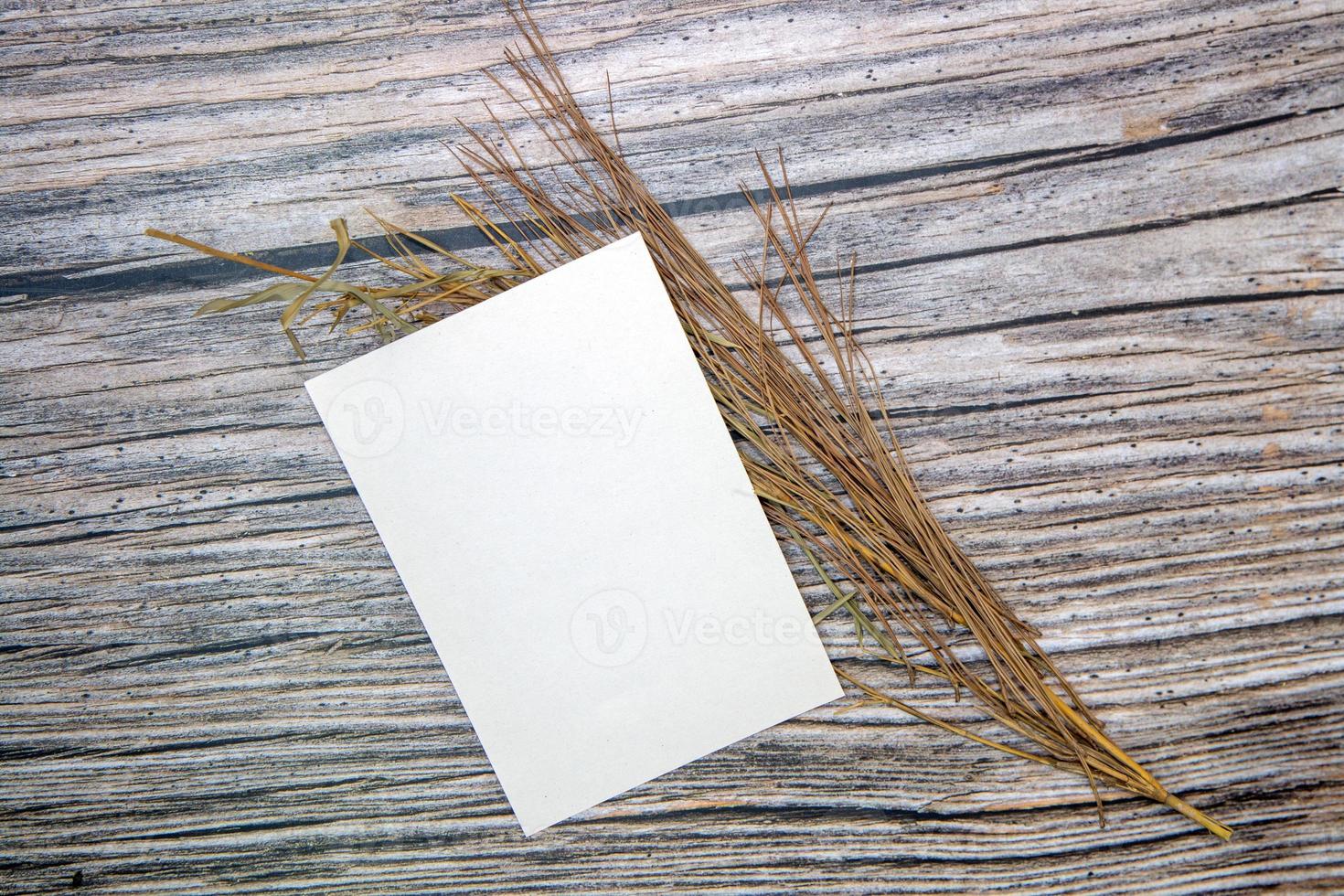 A5 paper greeting card mockup with dry leaves on wooden background photo