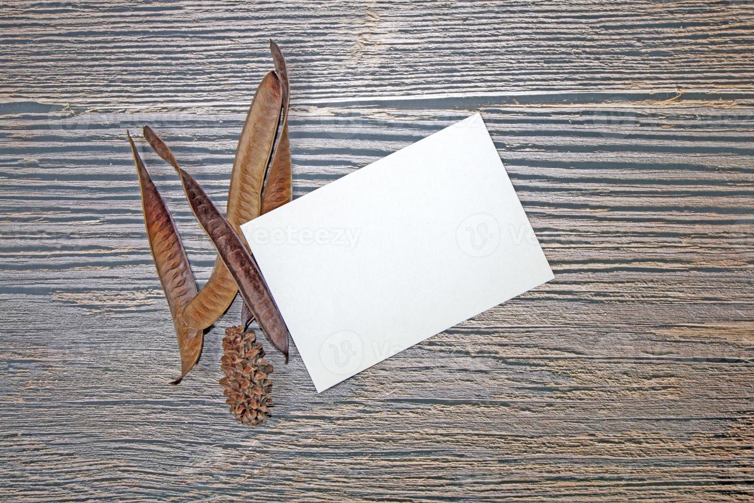 A5 paper greeting card mockup with dry leaves on wooden background photo