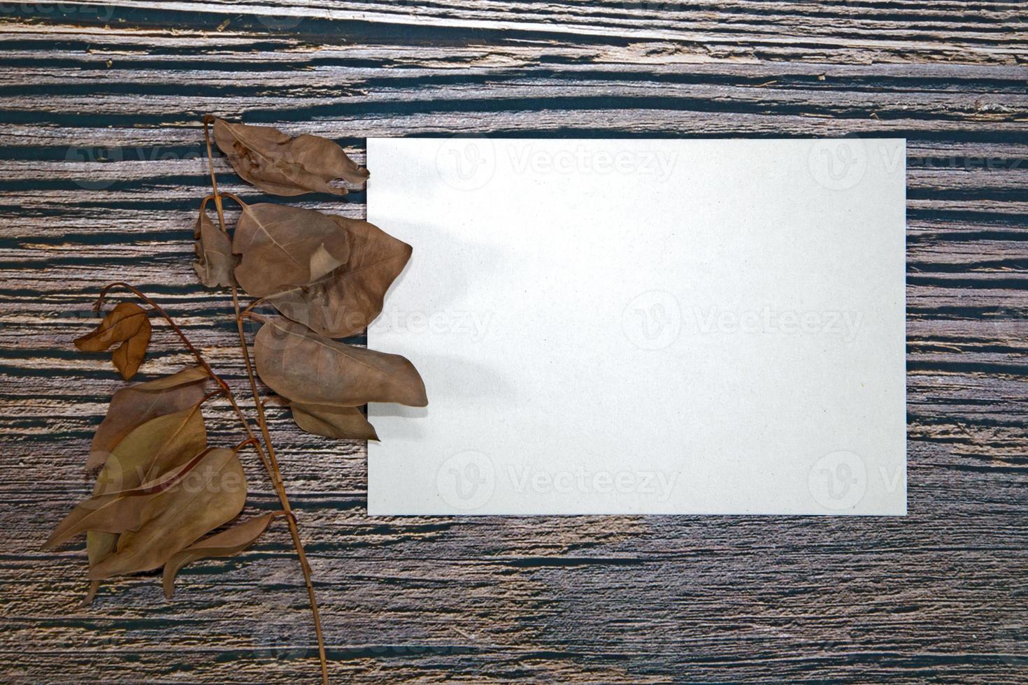 A5 paper greeting card mockup with dry leaves on wooden background photo