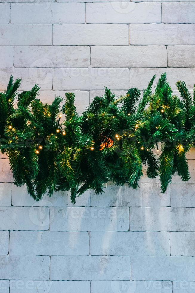 Christmas fir tree with lights on white brick background with copy space photo