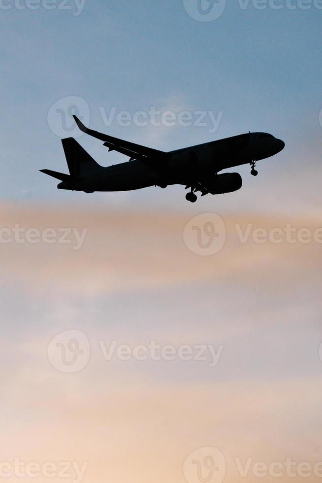 Silhouette of airplane in the sky at sunset with dramatic clouds photo