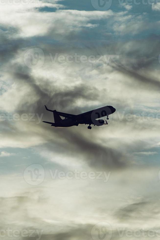 Silhouette of airplane in the sky at sunset with dramatic clouds photo