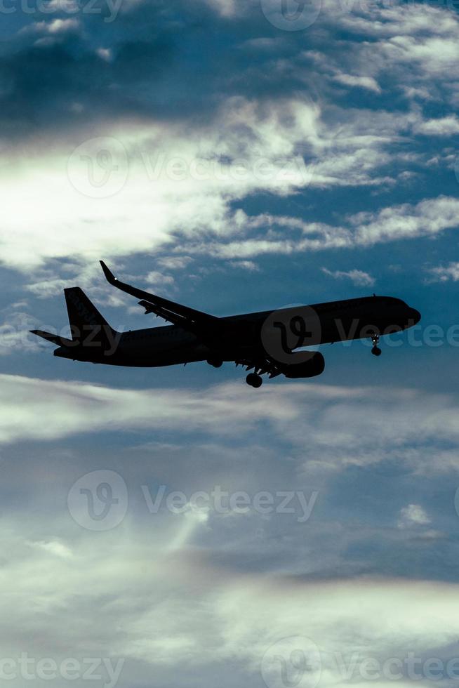 Silhouette of airplane in the sky at sunset with dramatic clouds photo