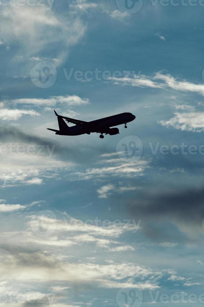 Silhouette of airplane in the sky at sunset with dramatic clouds photo