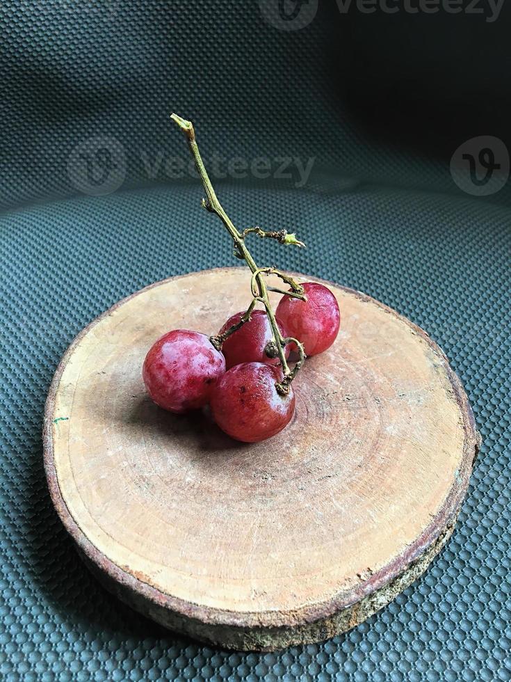 Still life with ripe pink grapes on a wooden plate photo