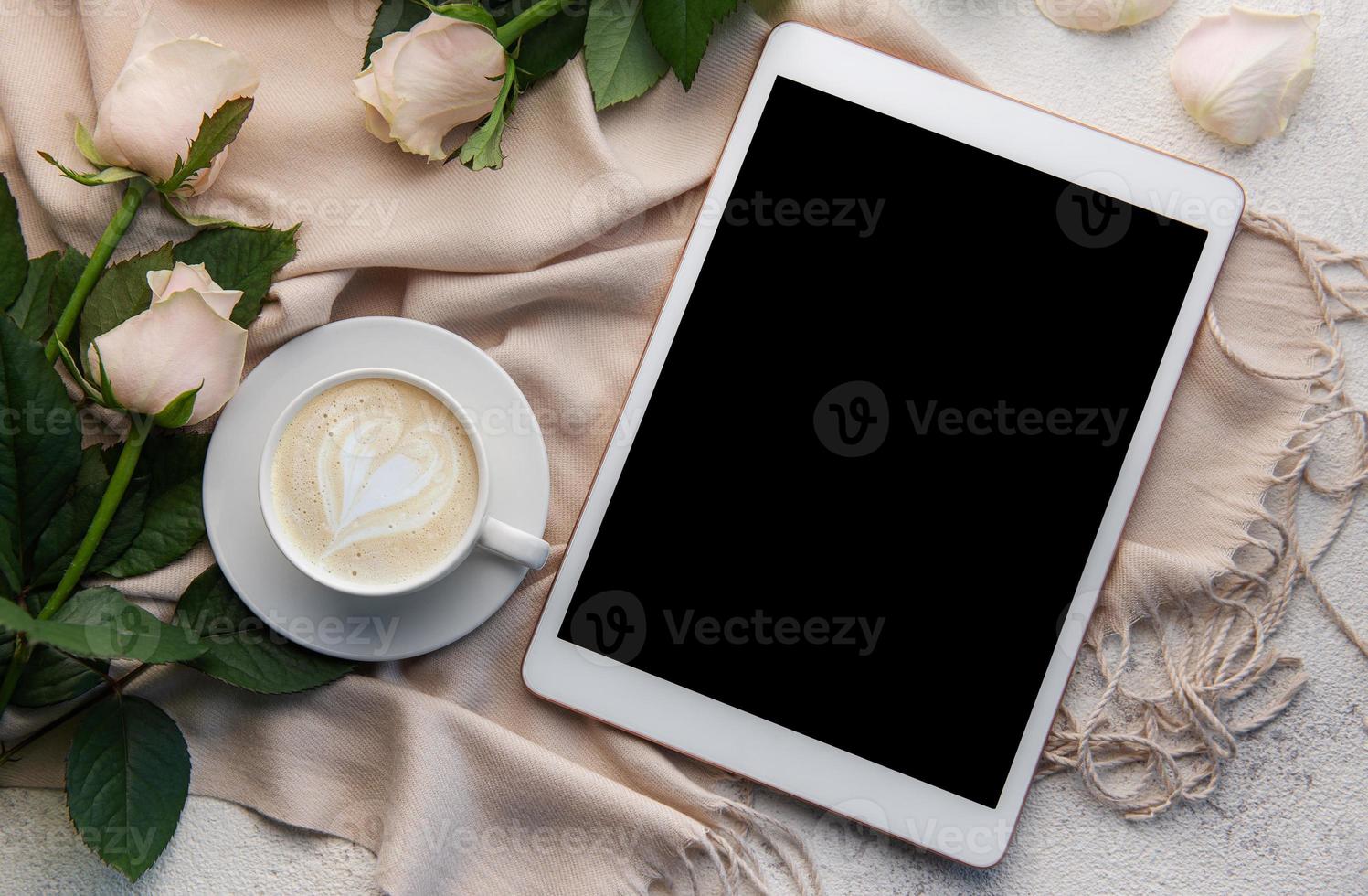 Top view a cup of coffee latte art heart shape with a pink rose and tablet photo