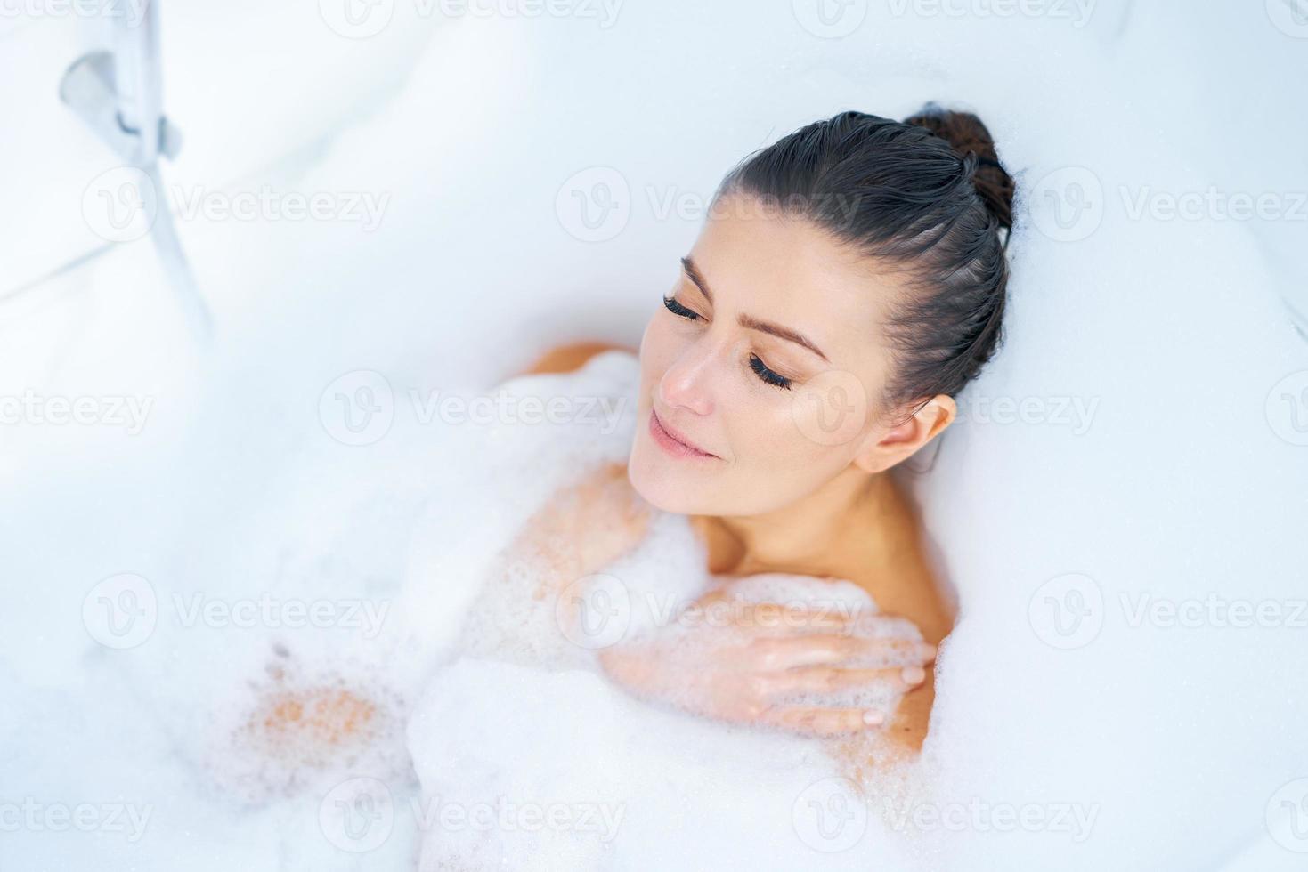 joven guapa morena mujer bañándose en la bañera foto