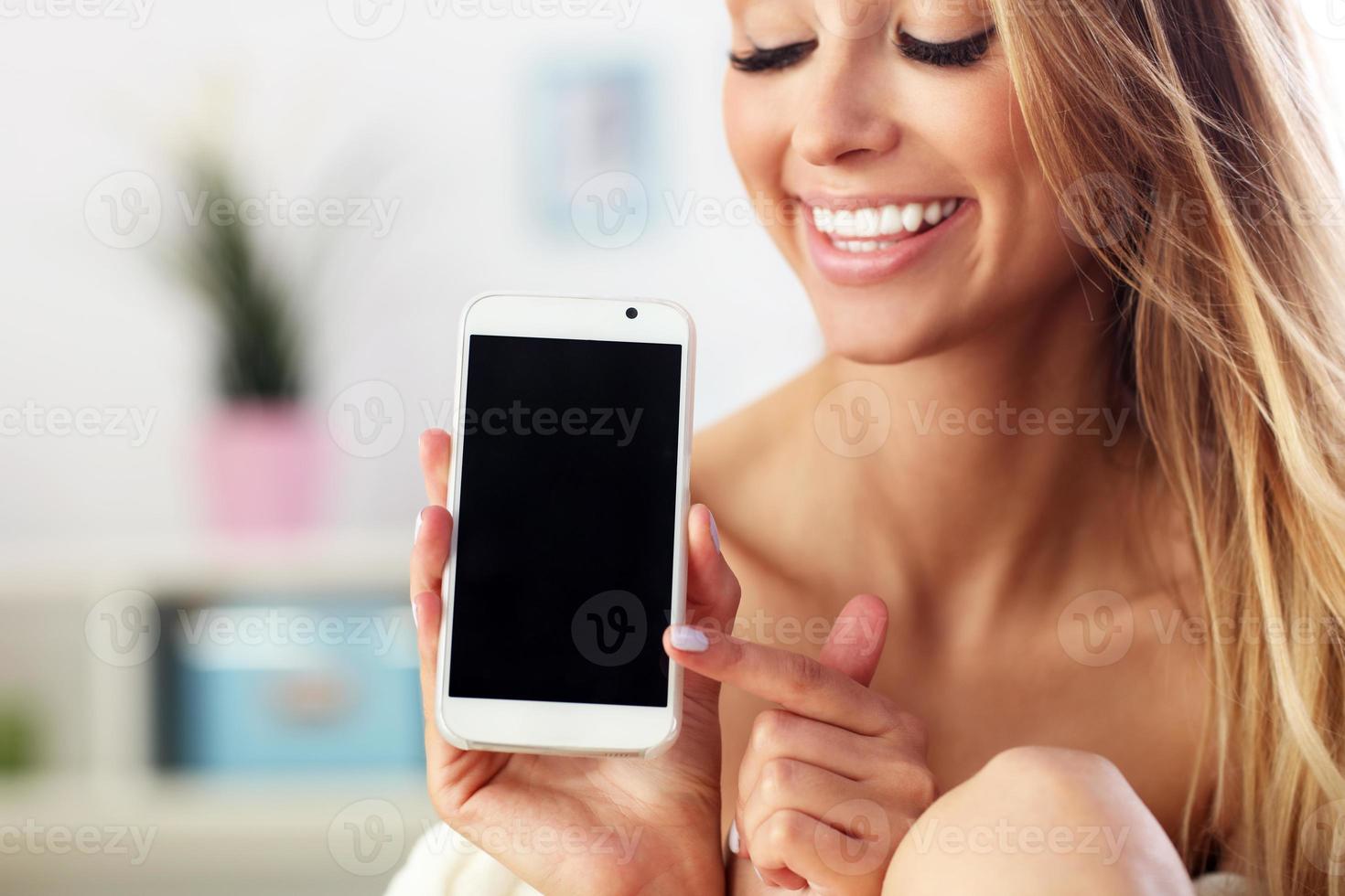 Happy woman with smartphone on sofa photo