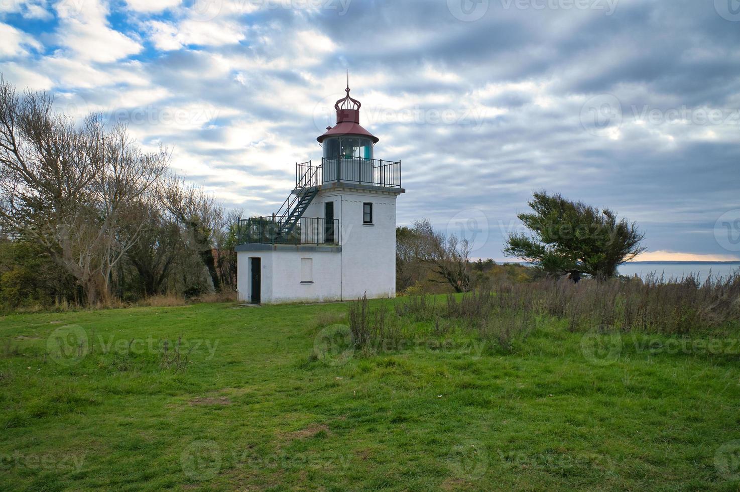 Lighthouse, Spodsbjerg Fyr in Huntsted on the coast of Denmark. Sun rays shining photo
