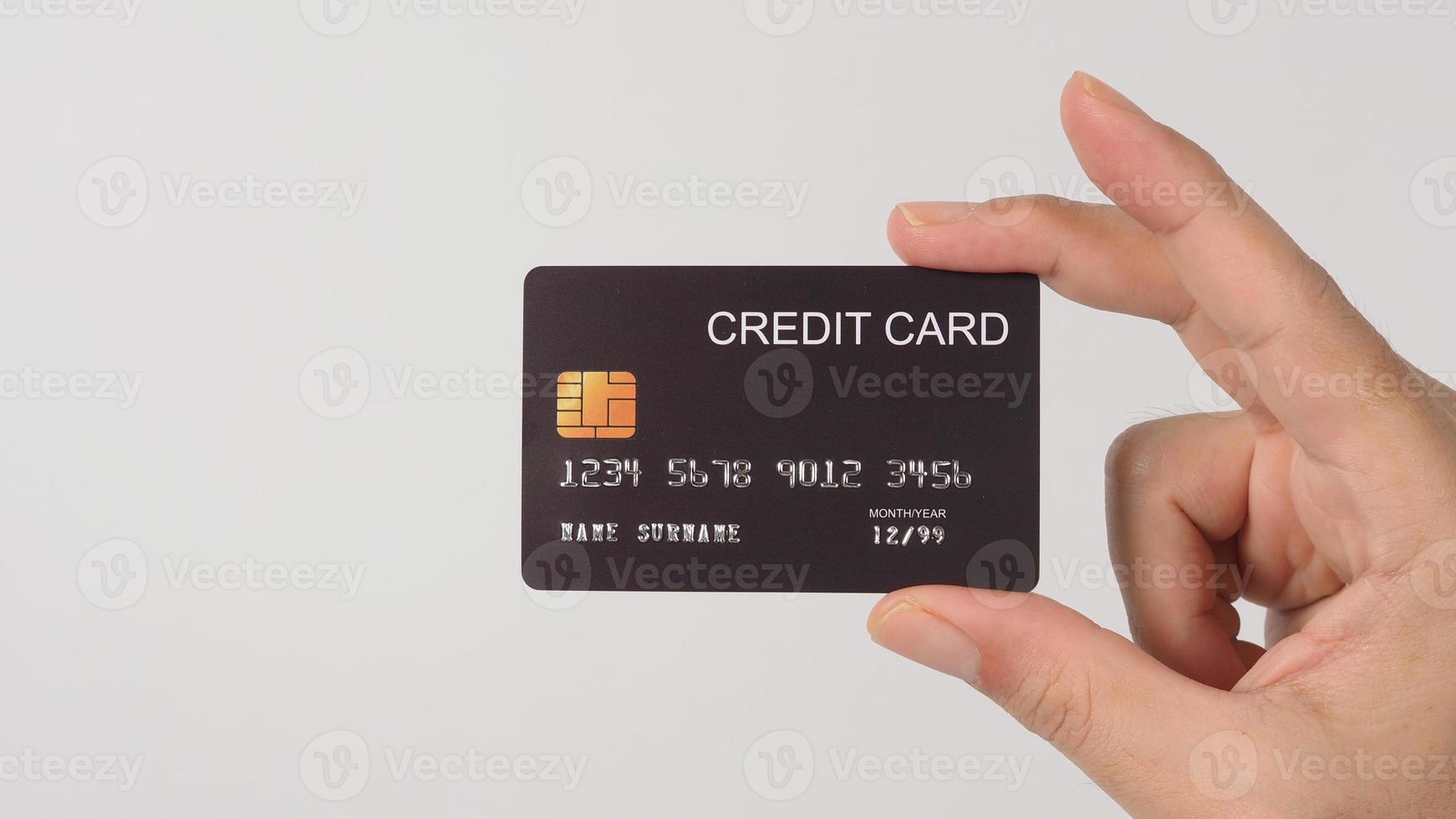 Hand is holding black credit card isolated on white background. photo