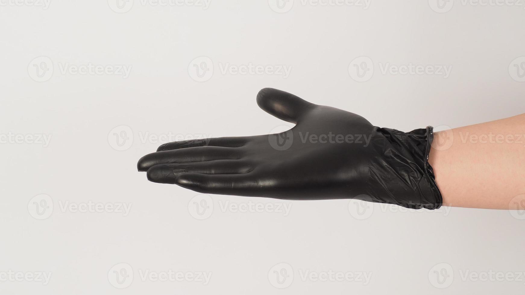 The hand is wearing a black latex glove and open the palm of the hand on white background. photo