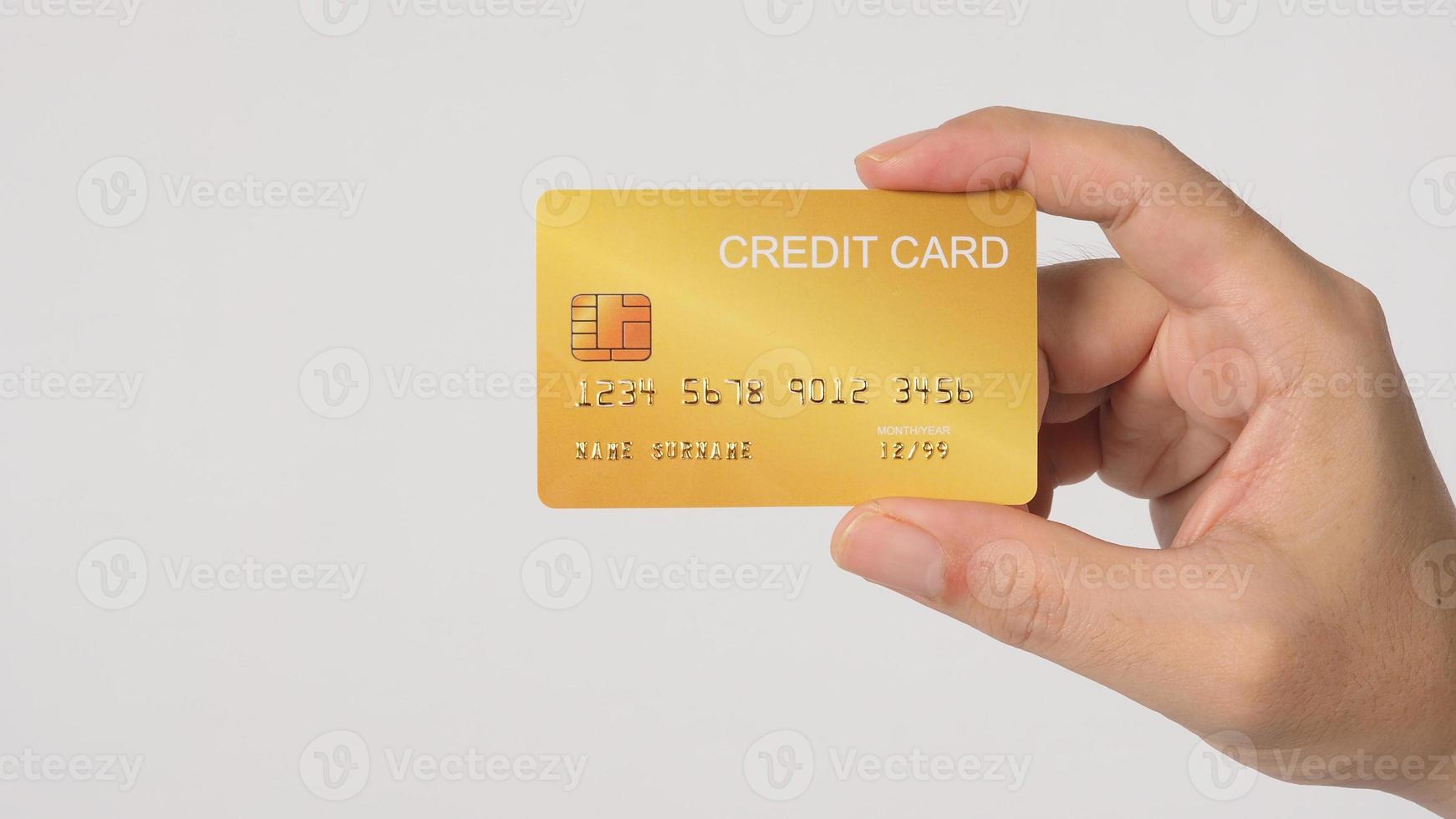 Hand is holding gold credit card isolated on white background. photo