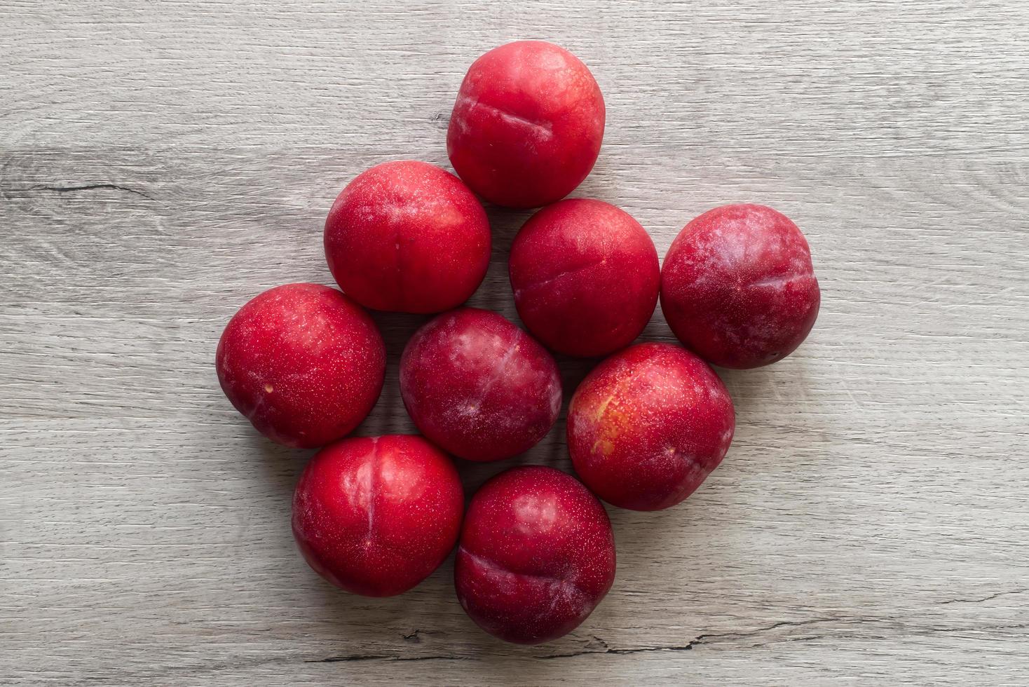 Fresh plums isolated on wooden table background photo
