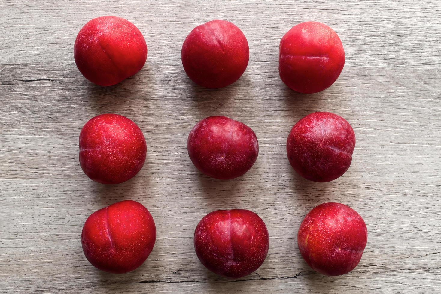 Fresh plums isolated on wooden table background photo