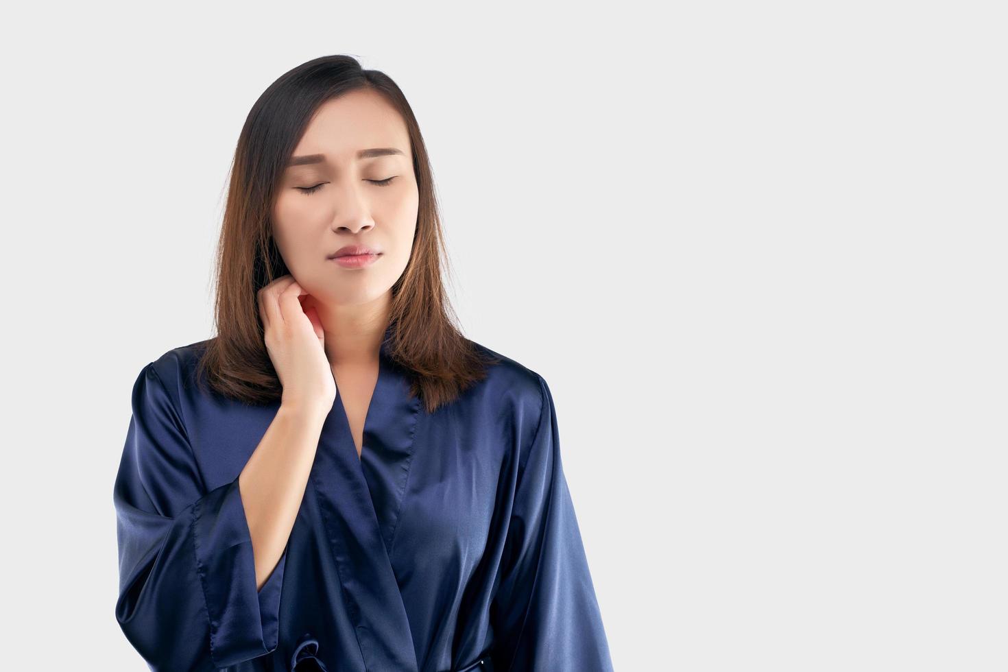 las mujeres asiáticas con túnica azul oscuro se rascan el cuello debido a la picazón en un fondo gris. la hembra tiene picazón en el brazo. el concepto de síntomas de alergia y atención médica foto