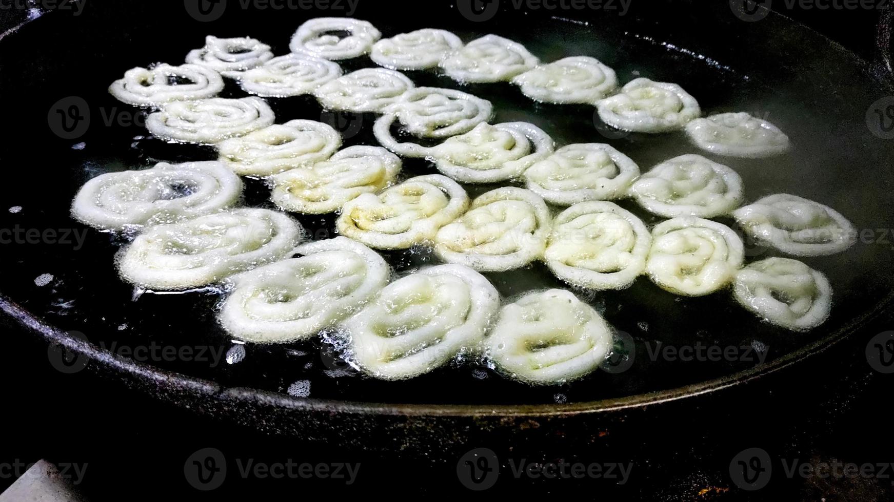 Indian jalebi frying in oil pan at stall photo