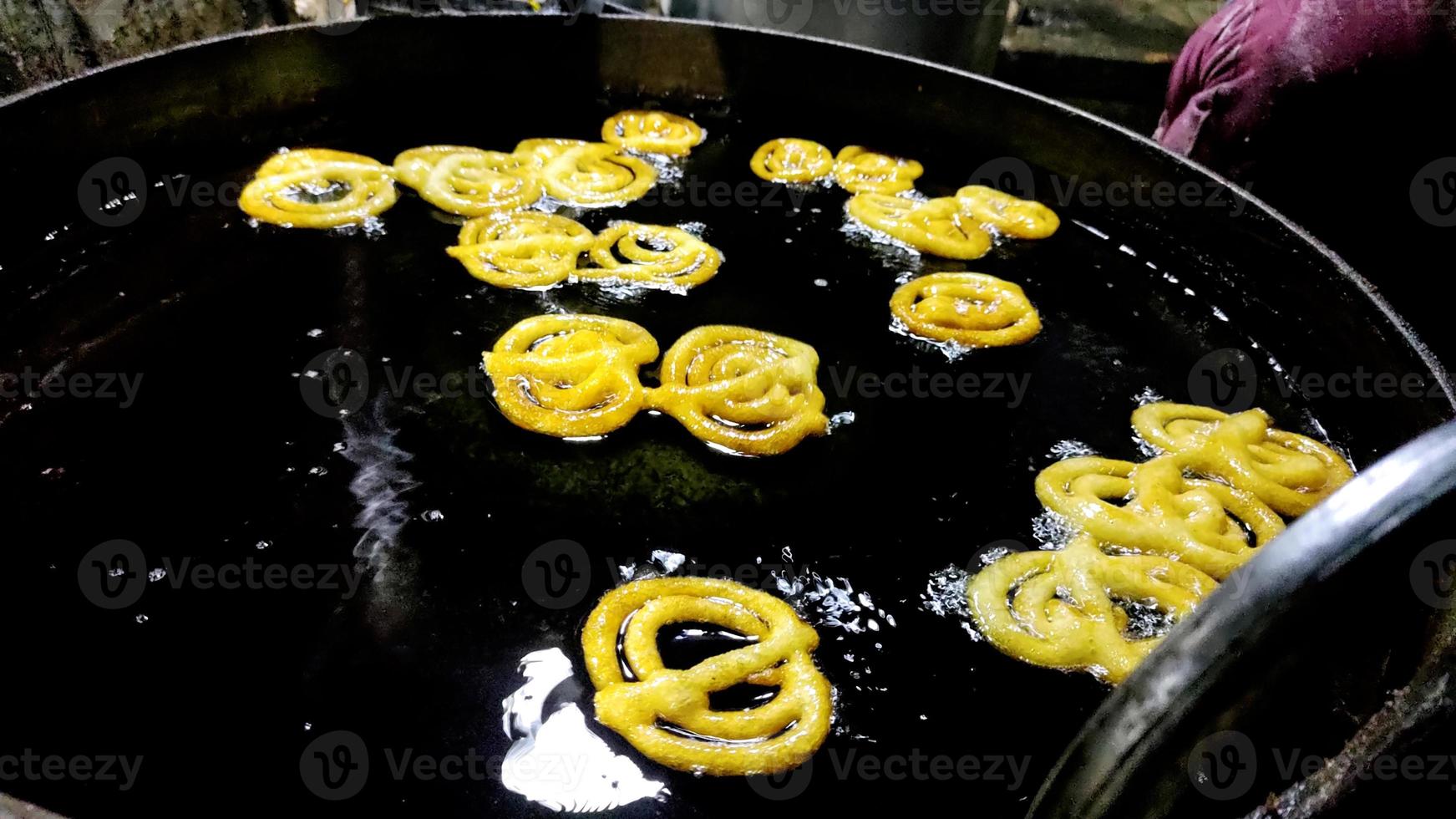 Jalebi indio freír en un cárter de aceite en el establo foto