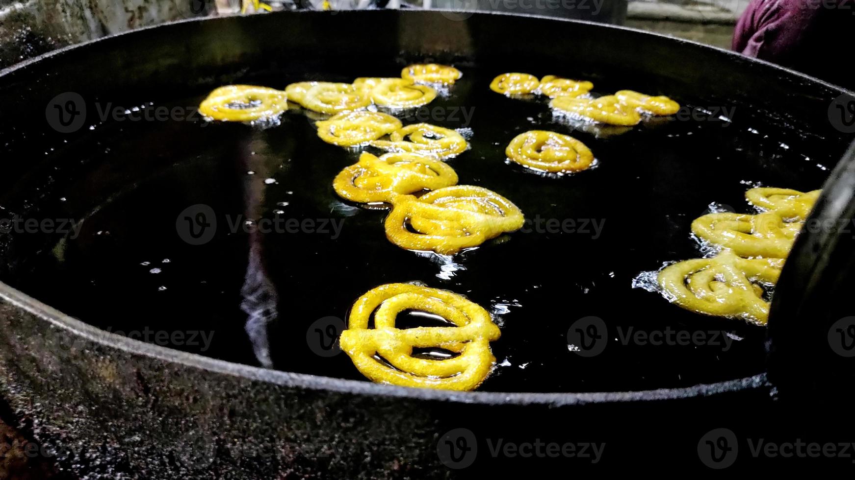 Indian jalebi frying in oil pan at stall photo