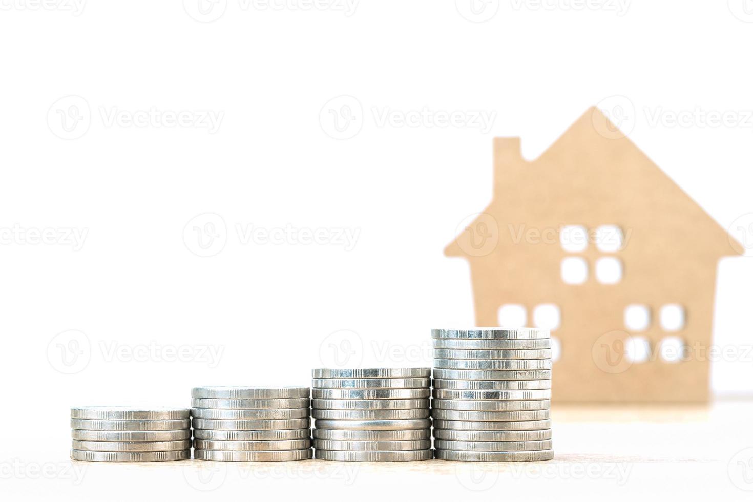 House model and stack of coins on table photo