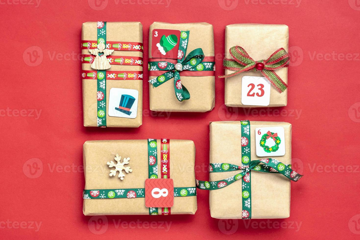 cajas de regalo rojas y verdes envueltas a mano decoradas con cintas, copos de nieve y números, adornos navideños y decoración en la mesa concepto de calendario de adviento de navidad vista superior banner de tarjeta navideña plana foto