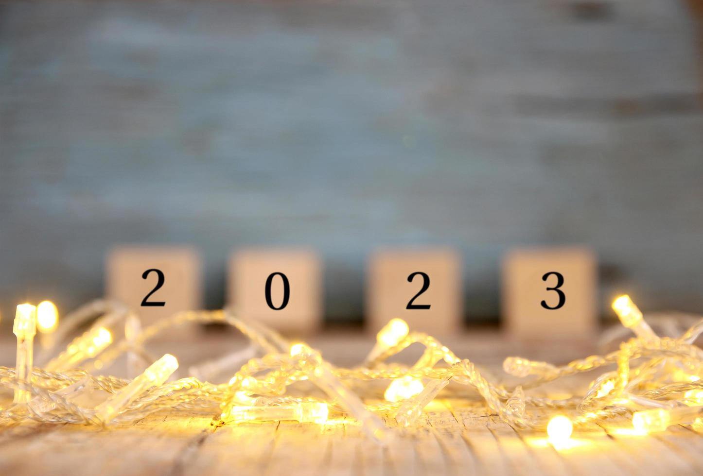 feliz año nuevo borroso 2023 en la mesa de madera y desenfoque de luz bokeh abstracta foto