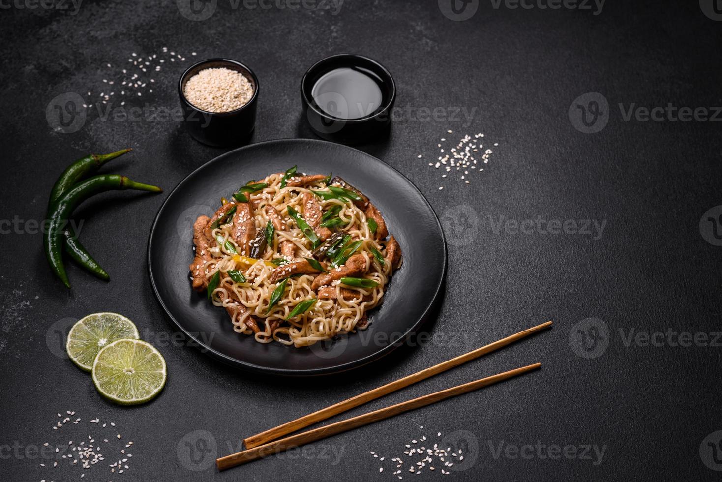 Tasty dish of Asian cuisine with rice noodles, chicken, asparagus, pepper, sesame seeds and soy sauce photo