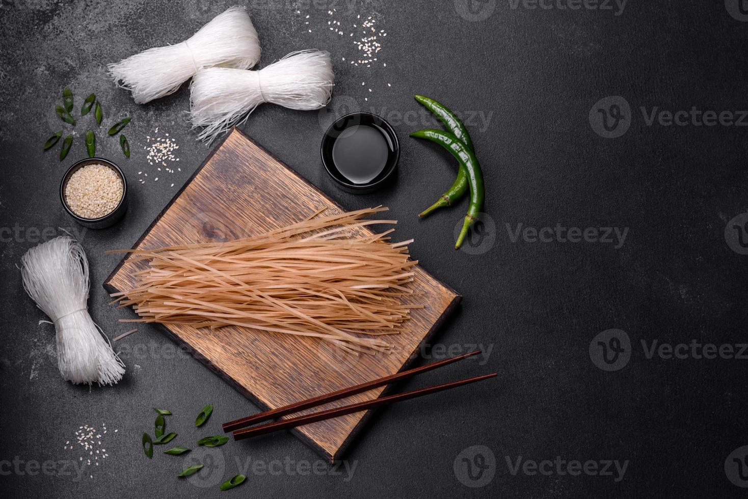 Tasty dish of Asian cuisine with rice noodles, chicken, asparagus, pepper, sesame seeds and soy sauce photo