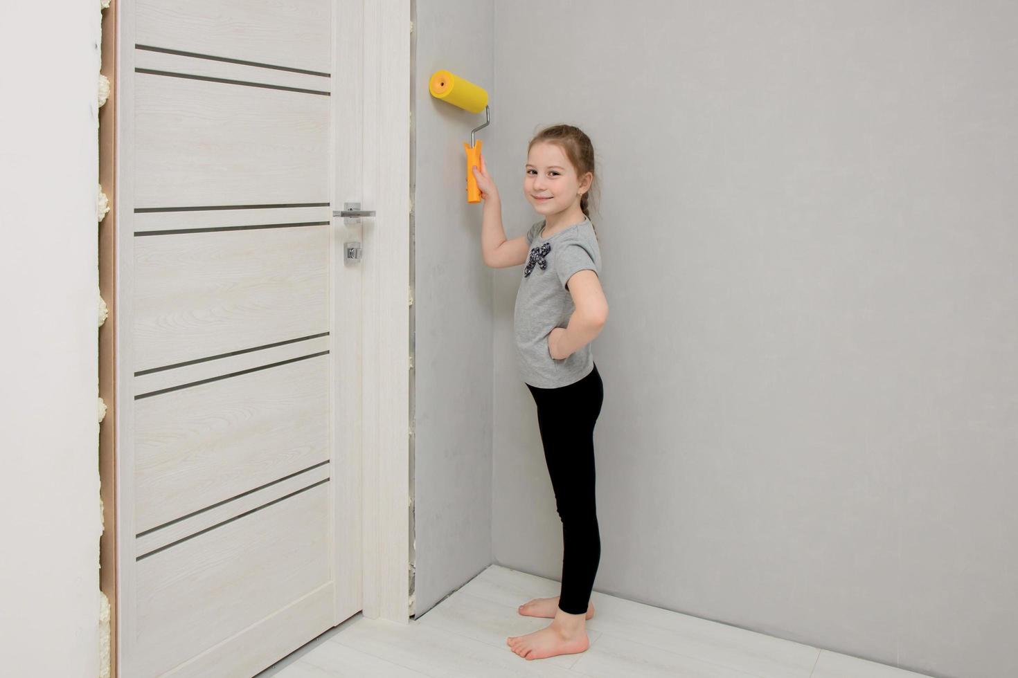 little girl drives along the wall with a paint roller in a house being renovated photo