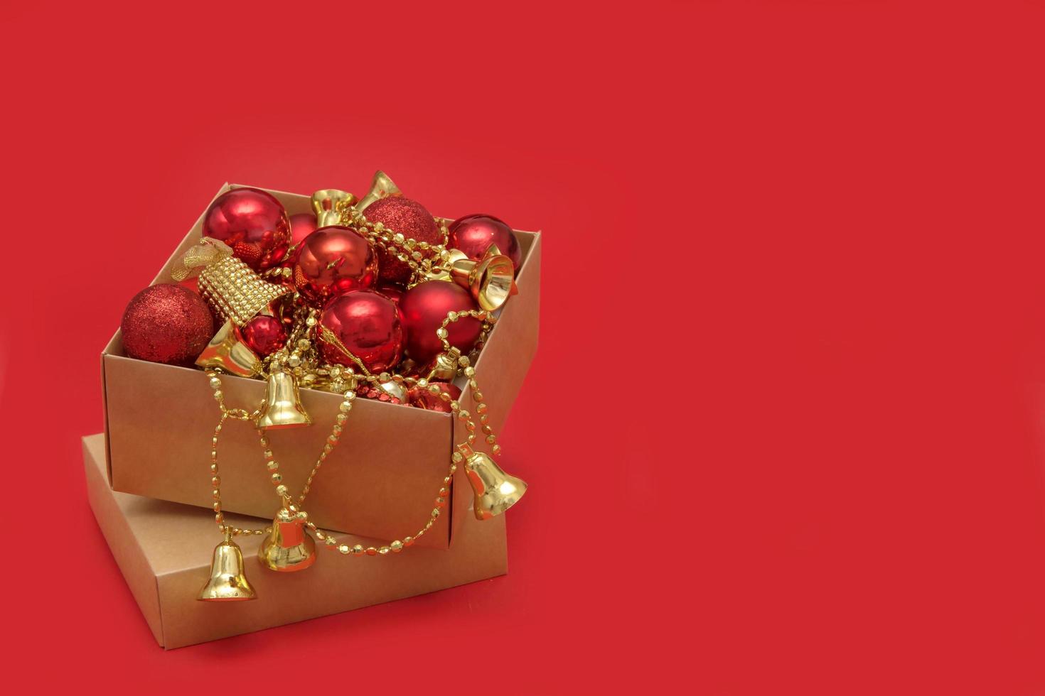 caja con juguetes para decorar el árbol de navidad en un fondo rojo con espacio para copiar, postal, felicitación foto