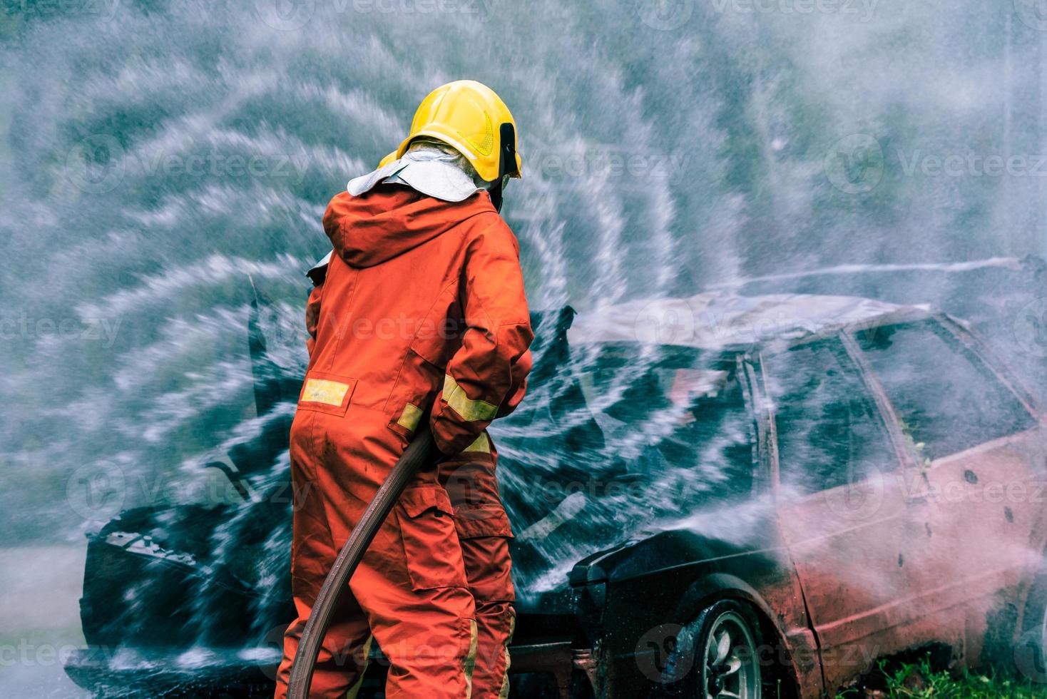Firefighter Rescue training to stop burning flame, Fireman wear hard hat and safety uniform suit for protection burn using hose with chemical water foam spray. photo