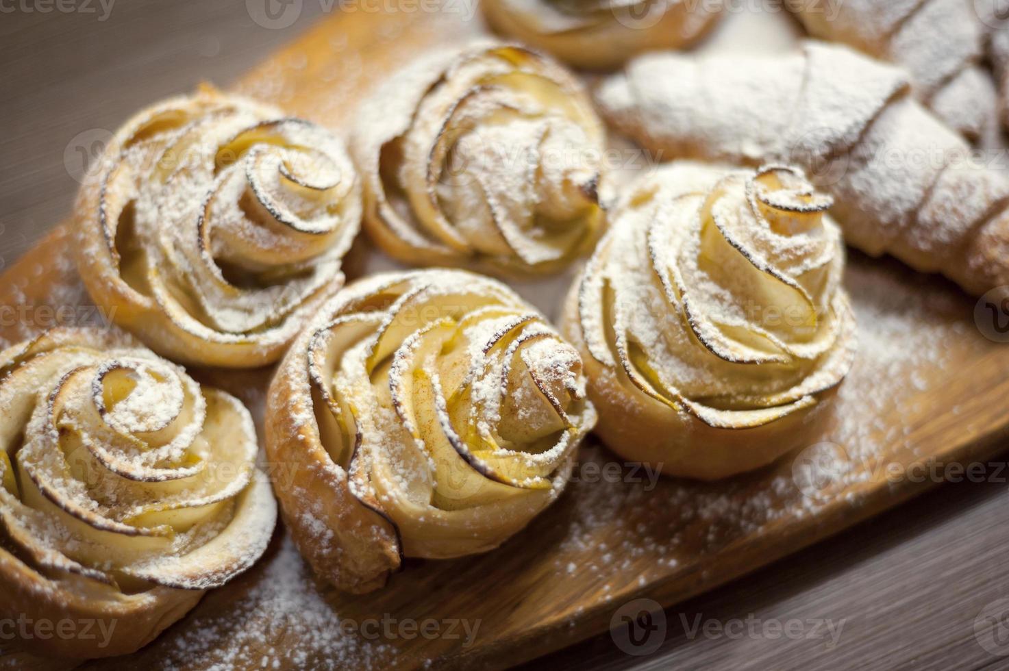 Close up of delicious croissants and pastries with apples, on a wooden Board in a cafe photo