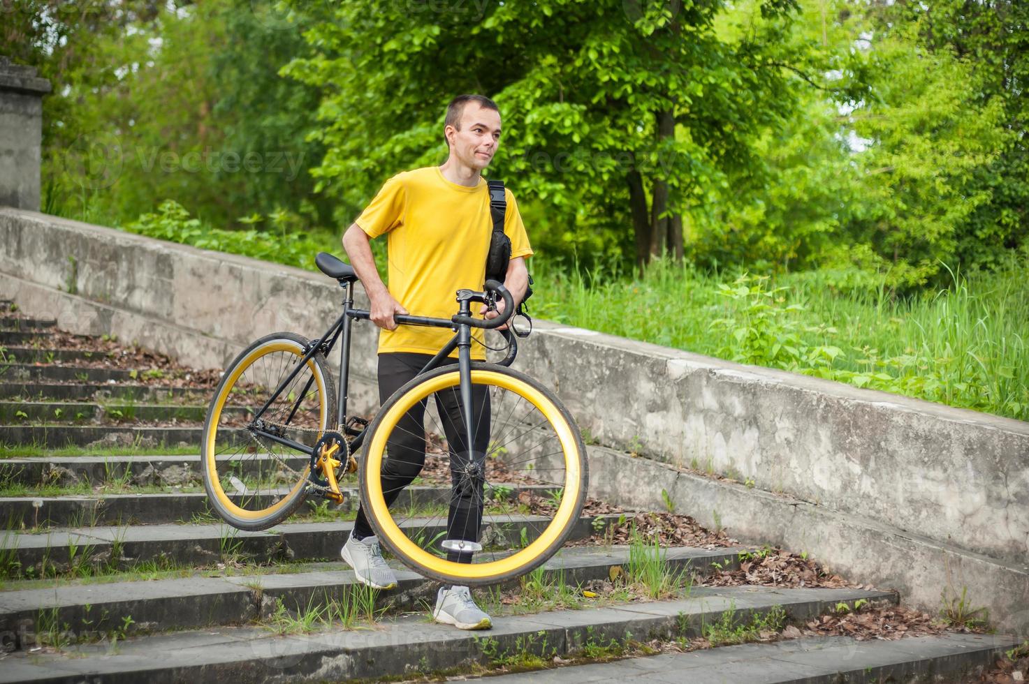 A young Man comes down the stairs with his Bicycle in a public Park. photo