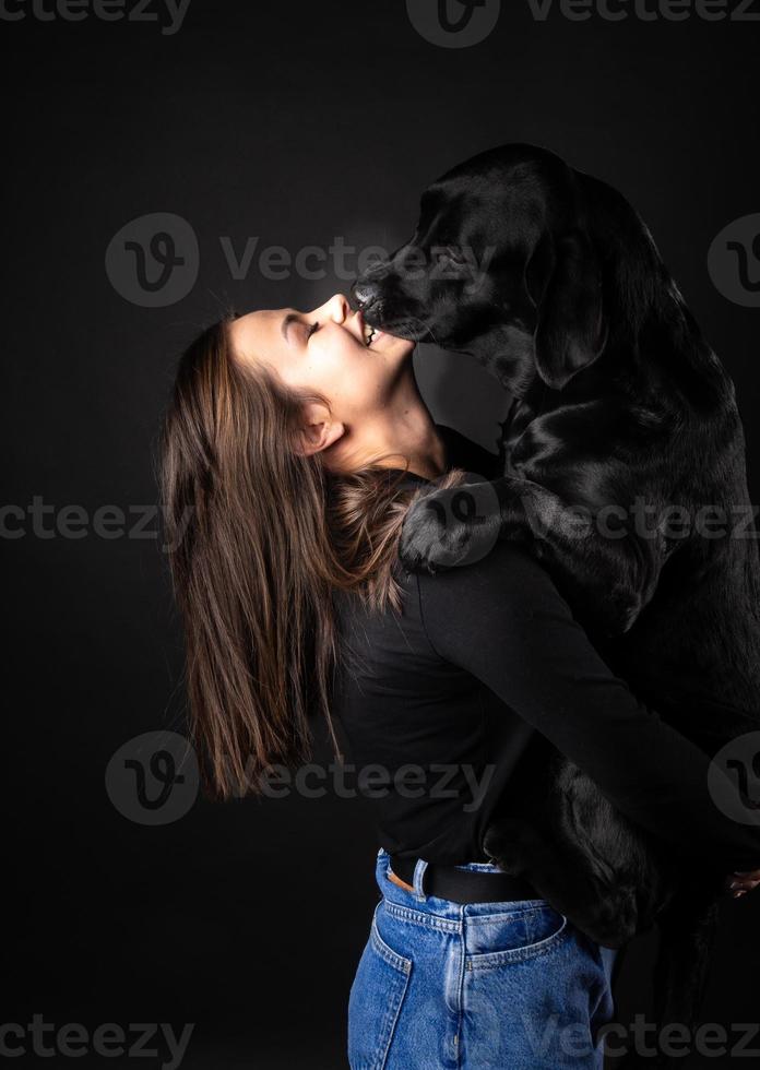 A girl holds a Labrador Retriever dog in her arms. photo