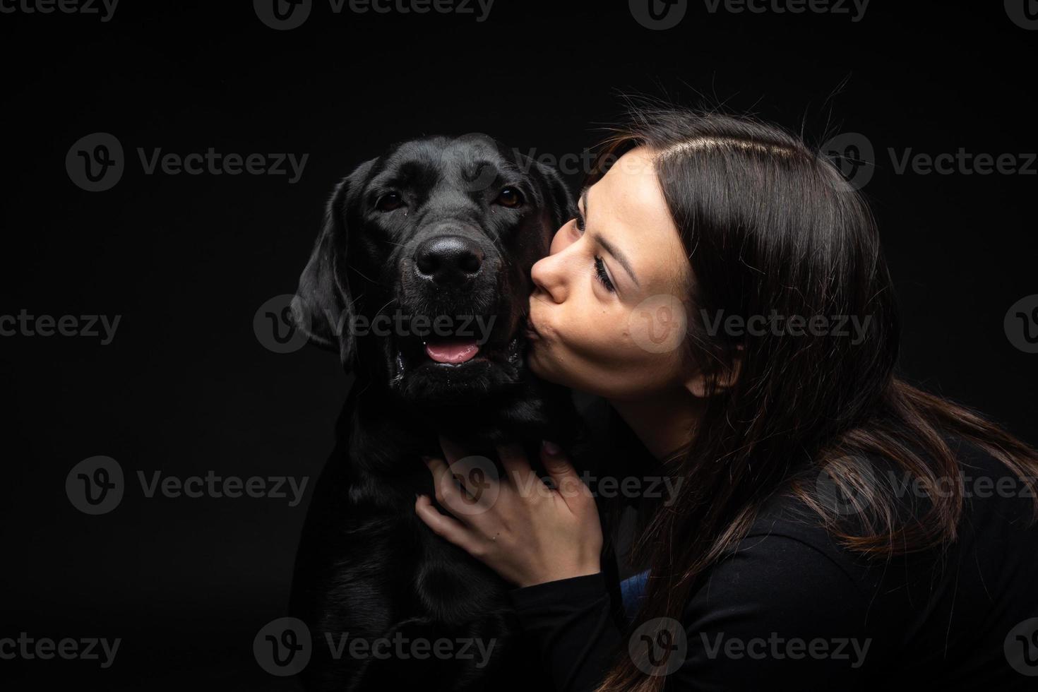 A girl holds a Labrador Retriever dog in her arms. photo