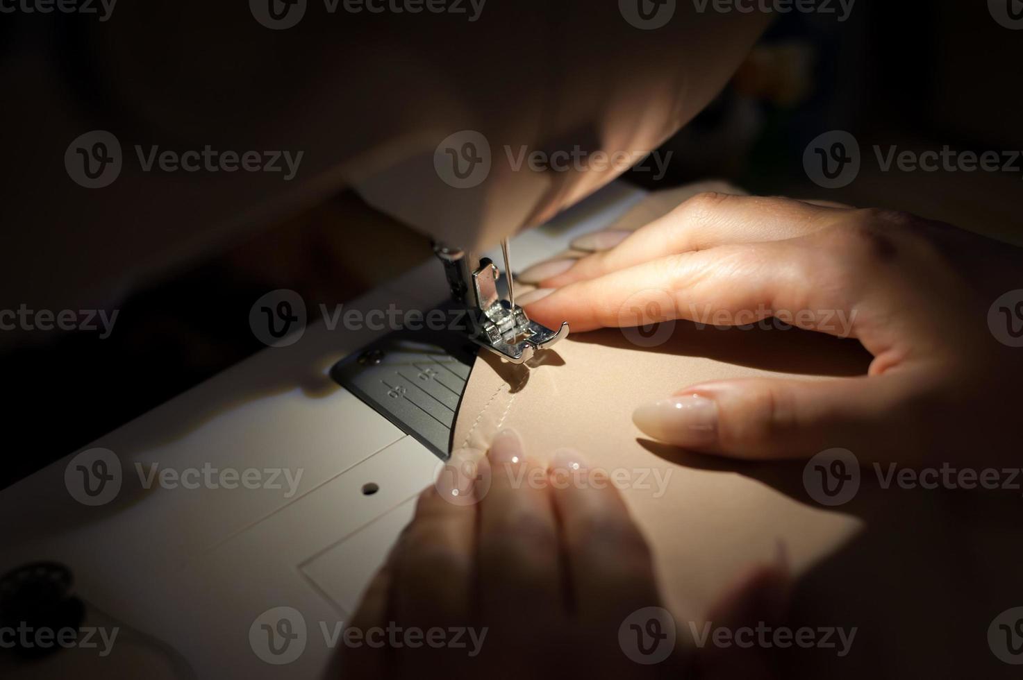 The woman is sewing with sewing machine. Sewing is one of the oldest of the textile arts. photo