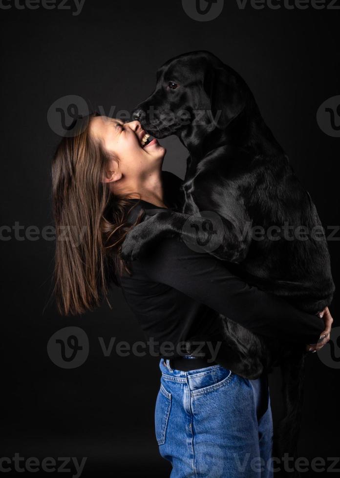 A girl holds a Labrador Retriever dog in her arms. photo