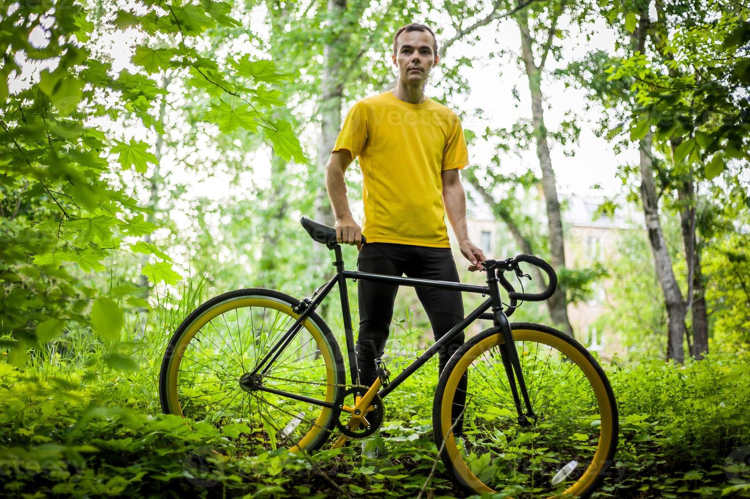 A young Man stopped to rest With his Bicycle in a public Park. photo