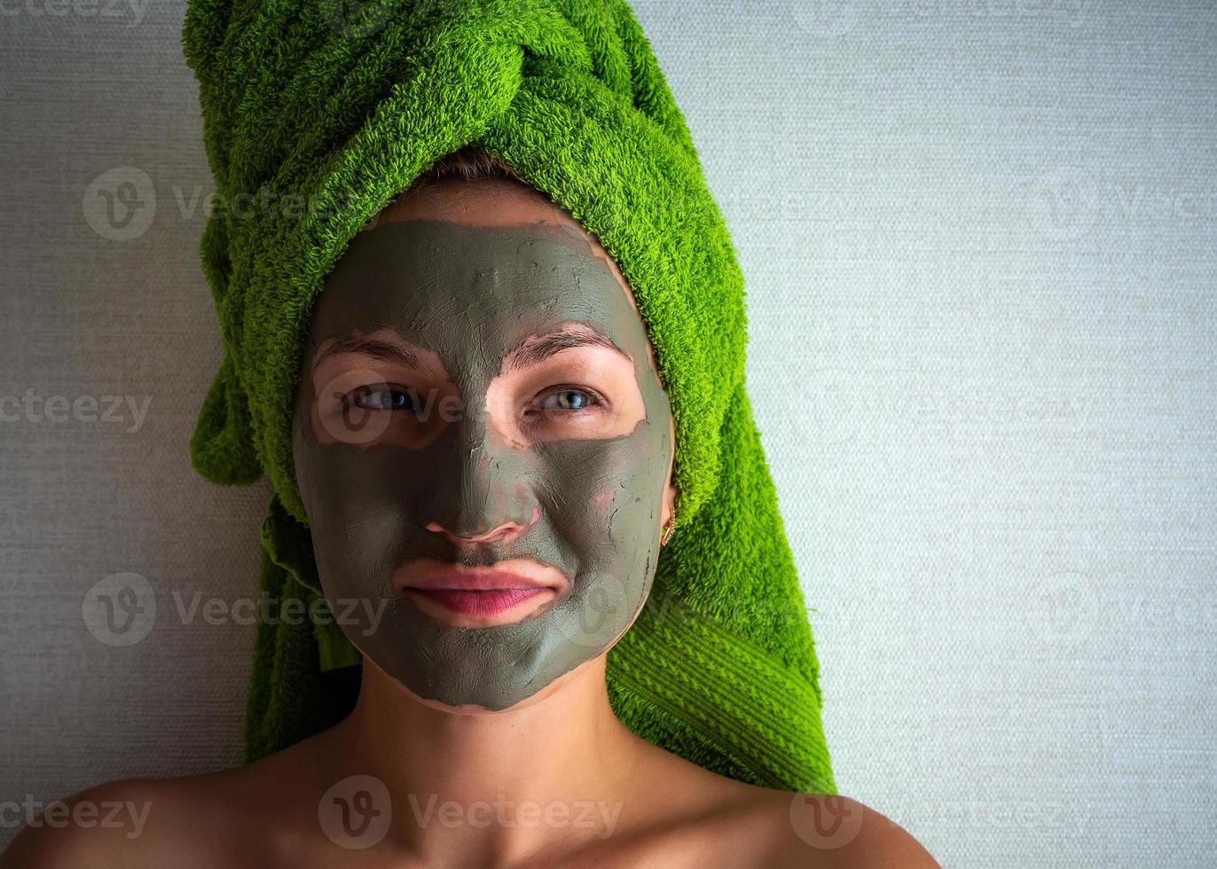 Young woman with clay mask on her face against light background, space for text. photo