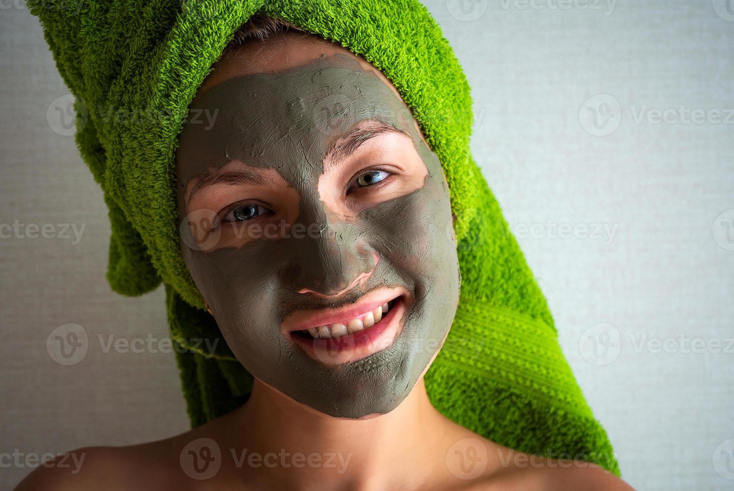 Young woman with clay mask on her face against light background, space for text. photo