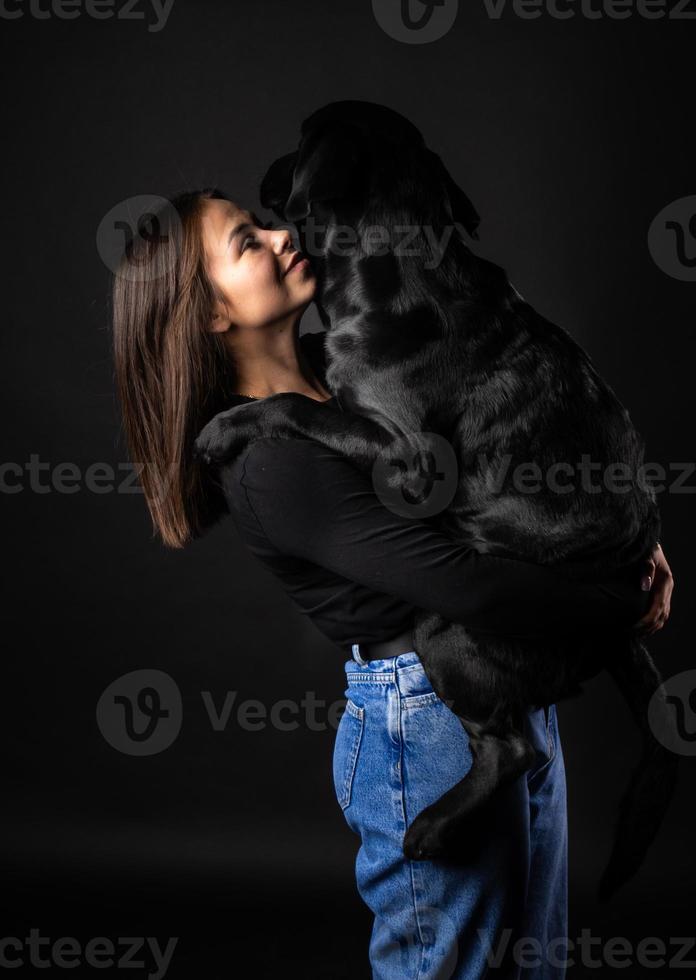 A girl holds a Labrador Retriever dog in her arms. photo