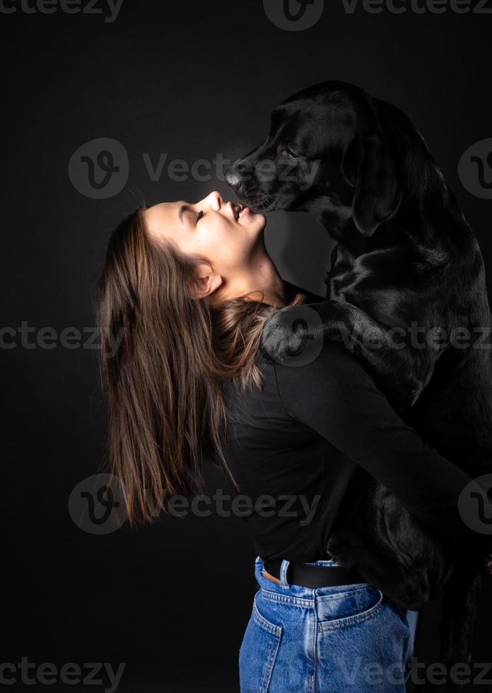 A girl holds a Labrador Retriever dog in her arms. photo