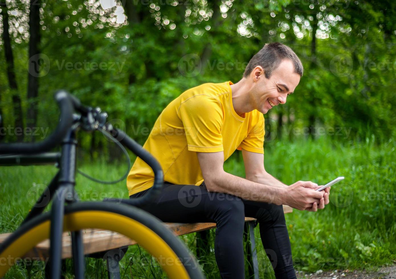 A young man sitting on a bench in a public Park communicates via mobile communication. photo