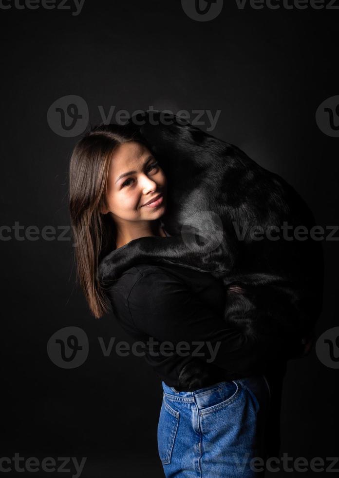 A girl holds a Labrador Retriever dog in her arms. photo