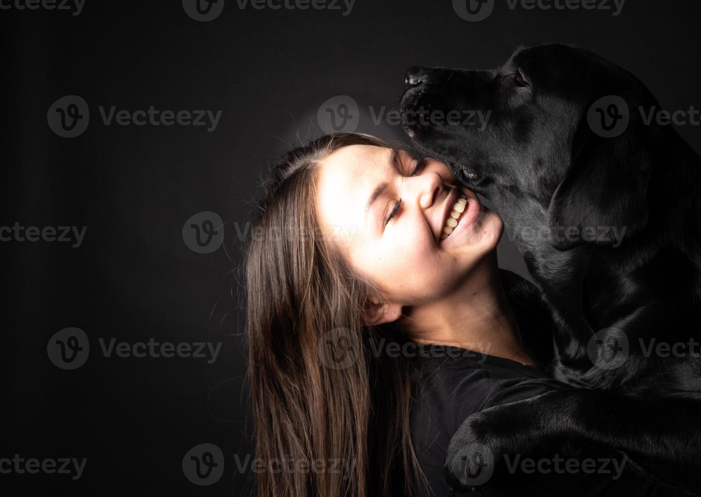 A girl holds a Labrador Retriever dog in her arms. photo